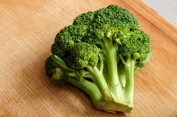 Half cut fresh broccoli on the wooden kitchen board , horizontal image, close up