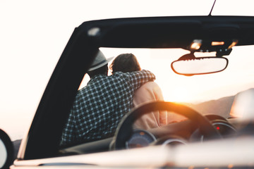 Young couple of travelers on cabriolet enjoy view and sunset