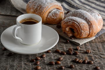 Fresh croissants and coffee on wooden table.