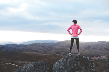 Obraz premium Athletic woman examines the landscape for training in the mountains. Sport tight clothes. 