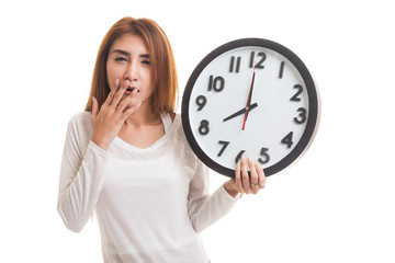 Sleepy young Asian woman with a clock in the morning.