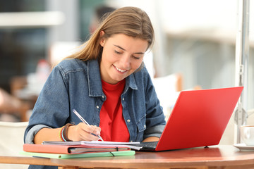 Student e-learning taking notes in a bar