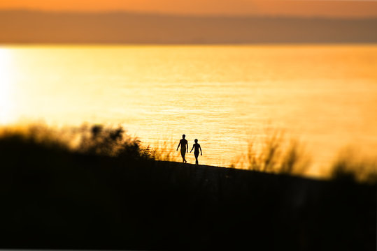 Couple, man and a woman, walking on the sand during the sunset. Blur effect. Abstract image. Love, friendship, relationship.