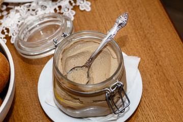 The chicken liver pate in a glass jar is on the table.