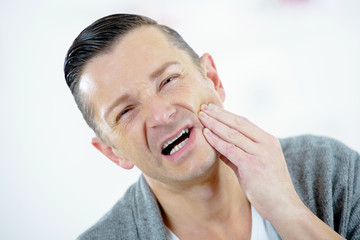 depressed ill man having toothache and touching cheek