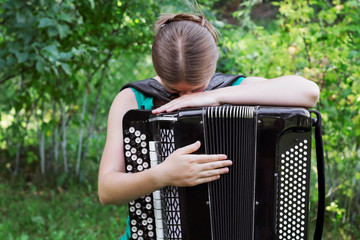 Girl musician plays the Russian bayan (button accordion). Musician, inspiration, nature.
