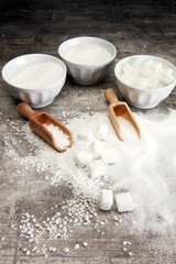 Bowl with white sand and lump sugar on grey background