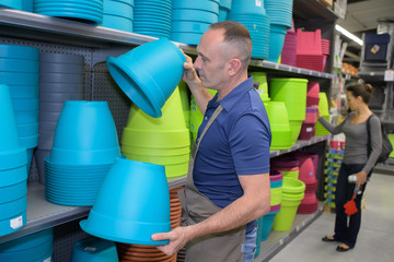 happy man tidying up flower pot in shop