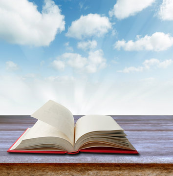 Open book on table in front of sky