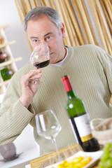 mature man enjoying a glass of red wine