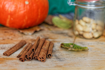 Cinnamon sticks, autumn leaves and pumpkin on a wooden table