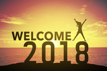 Silhouette young woman jumping and raising up her hand about happy concept on numbers 2018 over a beautiful sunset or sunrise at the sea, background for happy news years.success in 2018 years