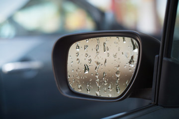 Left side car mirror showing rain droplets