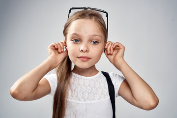 a little girl with glasses holds on to her ears, portrait, child