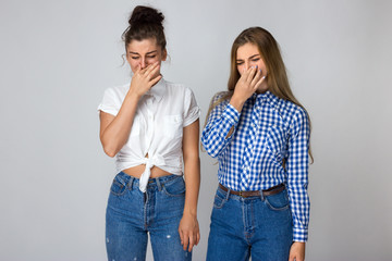 Two young sisters holding their nose because of a bad smell