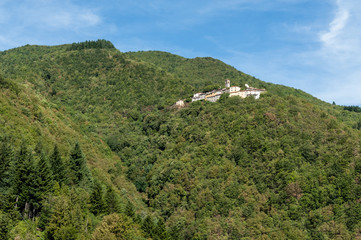 Small Italian medieval village called Sambuca Pistoiese built on the side of a mountain covered in lush forests on the Apennine Mountains in Tuscany, Italy.