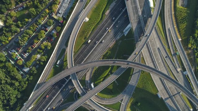 Multi-level road interchange and cars traffic. Drone is spinning around and flying up. Aerial vertical shot.