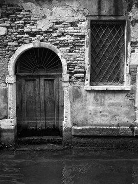 old door in venice opening on to a canal with stepe eroded bricks and square window