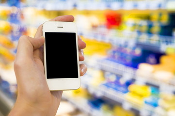 Man hand holding mobile smart phone on Supermarket blur background, business concept