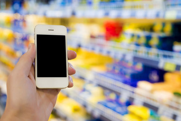 Man hand holding mobile smart phone on Supermarket blur background, business concept