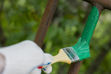 Hand wearing white gloves and painting with a paint brush.