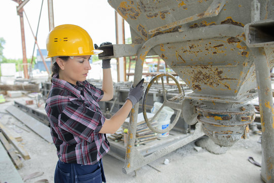 female worker mixing ingredients in the concrete mixer