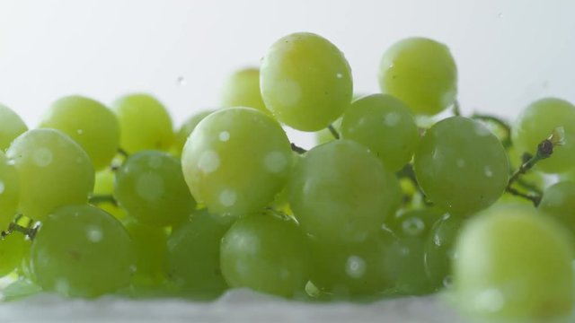 Green grapes falling on water surface. Shot with high speed camera, phantom flex 4K. Slow Motion.