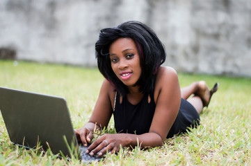 Beautiful business woman laying on grass and using laptop