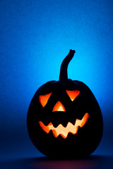 Halloween pumpkin, silhouette of funny face on blue background.