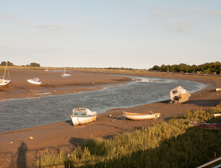 a bunch of parked moored boats on the beach of stream river maldon black water essex - Powered by Adobe