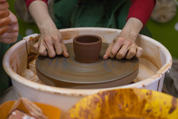 Master cuts thread pottery with the Potter's wheel. The master teaches the student of ceramics. Work in the pottery workshop. The Potter's wheel in operation.
