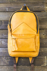Yellow leather backpack for traveler on the wooden background