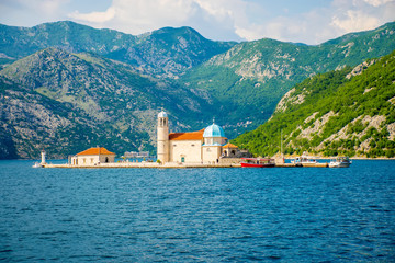 Fototapeta na wymiar The yacht sails near the picturesque Gospa od Skrpela Island in the Boka Kotorsky Bay.