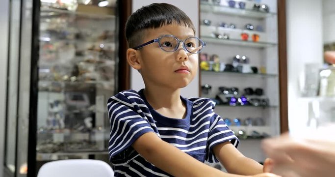 Little boy trying glasses in optical shop