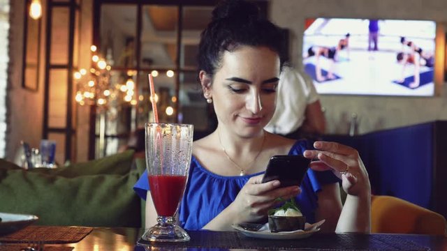 Girl is making photo with her phablet of her delicious pasta with mussels in tomato souce in a restaurant. 4K.