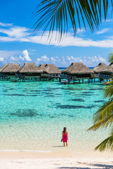 Luxury beach travel vacation woman in Tahiti. Tourist enjoying ocean water at overwater bungalow hotel villas in French Polynesia, Moorea island in south pacific, famous getaway destination. - obrazy, fototapety, plakaty