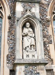 statue of man on the outside of english christian church made of stone