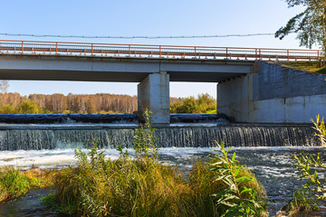 Waterfall on the river Suenga under a highway bridge. Siberia, Russia