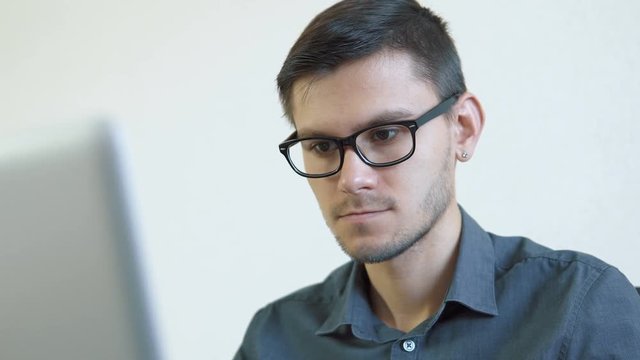 Portrait of a young man wearing glasses sitting in front of a monitor - making a purchase using a credit card online. People stock footage slider shot. 