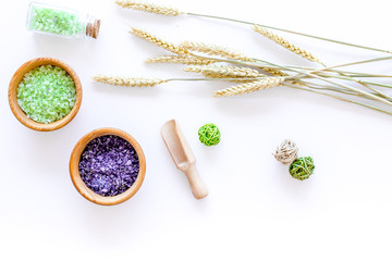cosmetic set with wheat herbs and sea salt in bottle on white table background flat lay