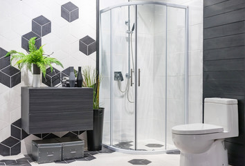 Modern spacious bathroom with bright tiles with glass shower, toilet and sink. Side view