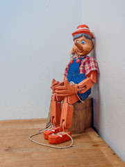 Pinocchio puppet made from wood.Sitting on wood box - obrazy, fototapety, plakaty