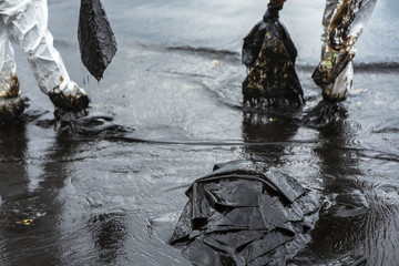Workers remove and clean up crude oil spilled with absorbent paper