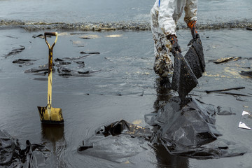 Workers remove and clean up crude oil spilled with absorbent paper