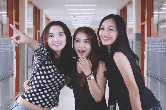 Three female students are pointing at something