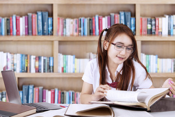 Pretty teenage student learns in library