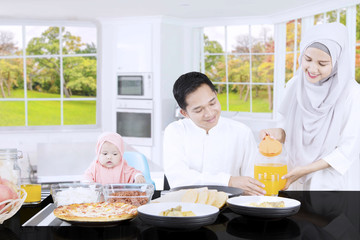 Muslim mother pouring orange juice