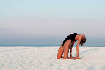 Beautiful woman doing yoga on the beach