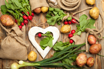 Raw garden radish, onions and potatoes on a wooden background