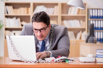 Obraz premium Young businessman addicted to online gambling cards playing in t